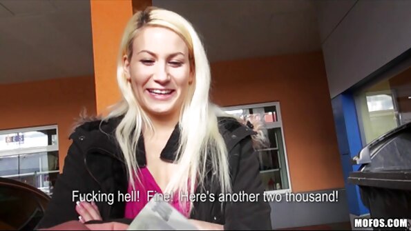 ஒரு பொன்னிற பெண் மேஜையில் இருக்கிறாள், அவள் தனது பெரிய பொம்மையைப் பயன்படுத்துகிறாள்